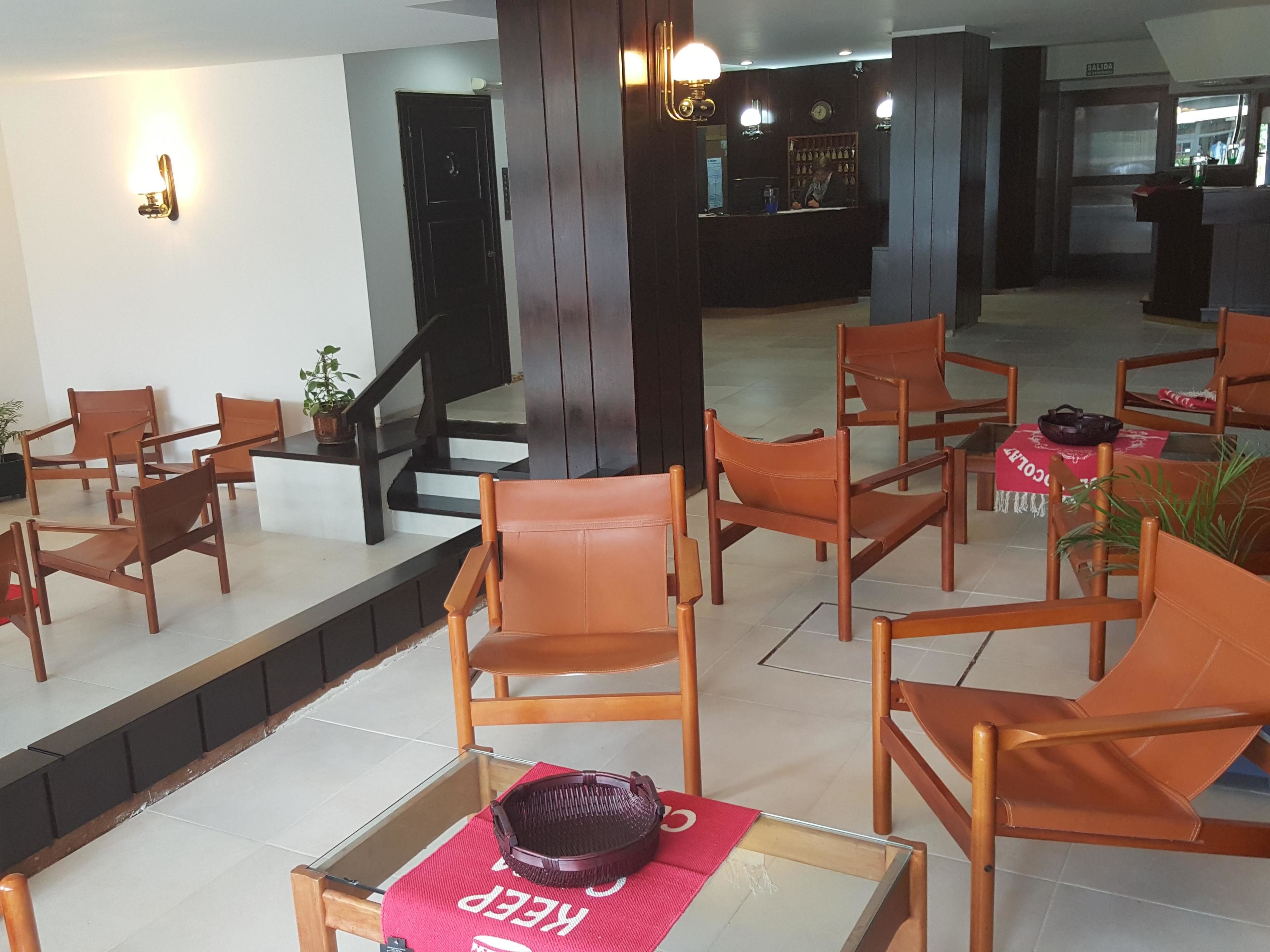 Un vestíbulo con sillas de madera, un mostrador de recepción y una escalera.