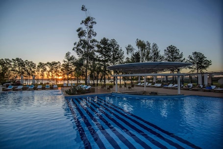 Una piscina al aire libre, sombrillas, sillones reclinables de piscina
