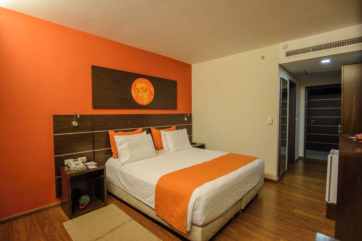 A bedroom with a bed, nightstand, and a wall-mounted artwork.