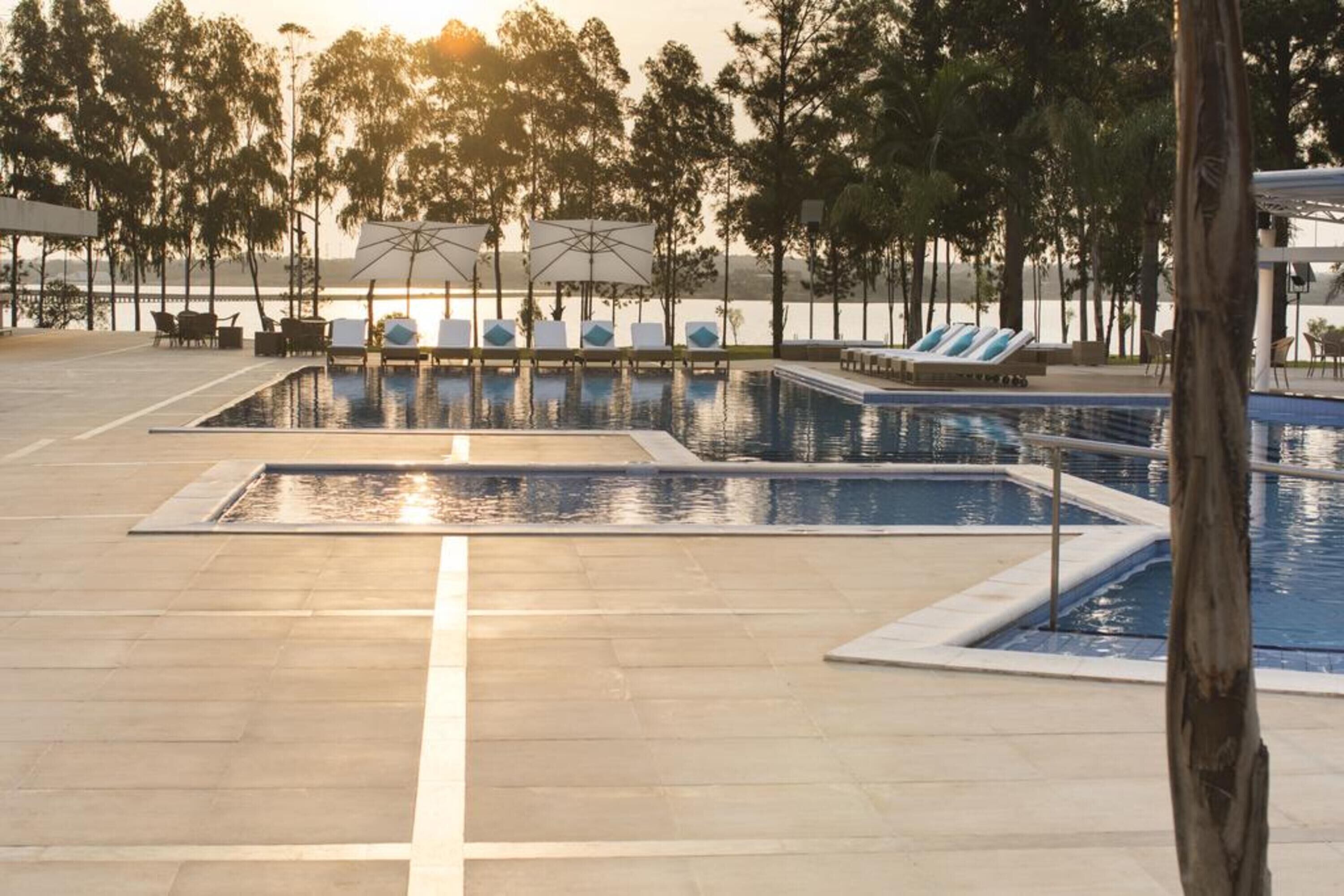 A pool area with multiple swimming pools, lounge chairs, and umbrellas.