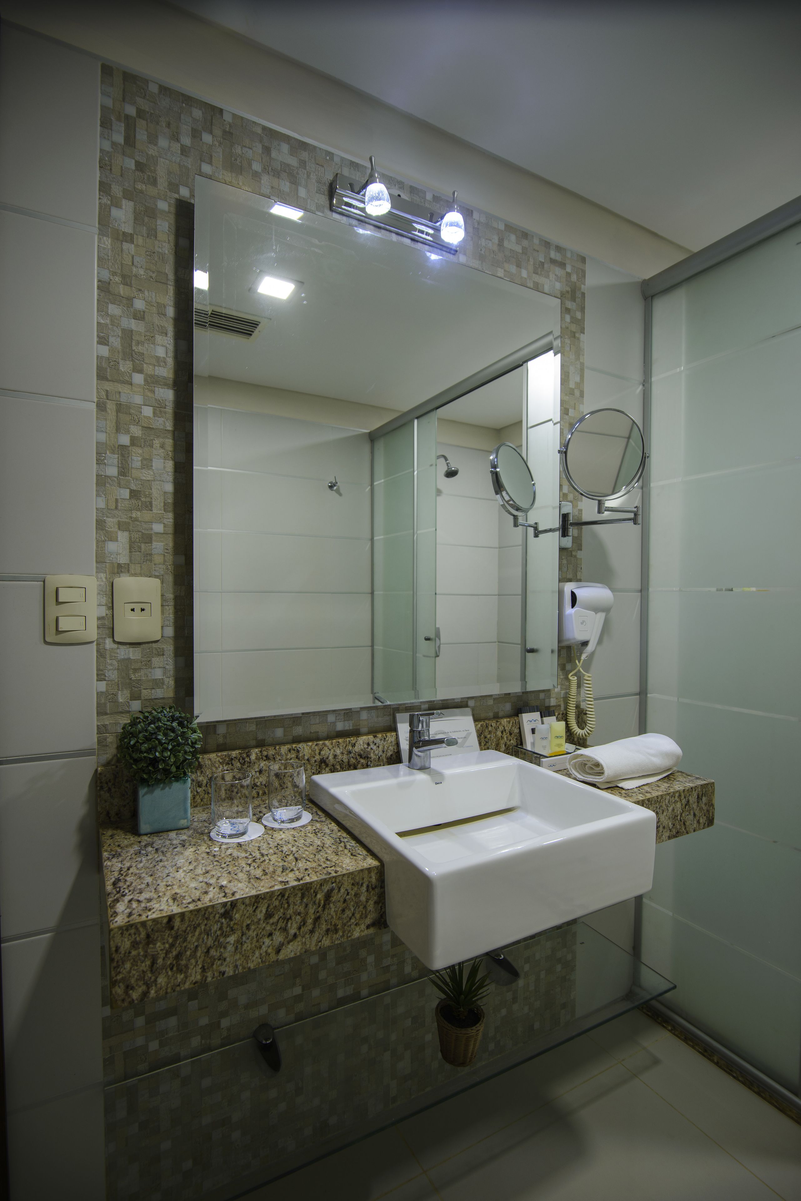A modern bathroom with a large mirror, a sink, and a hairdryer.