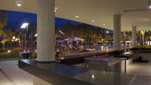 Comedor interior y exterior con mesas y sillas, una piscina y una zona de bar.