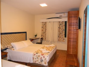 A bedroom with a bed, a desk, a chair, an air conditioning unit, and a wooden door. - Recanto da Prainha (Torres)
