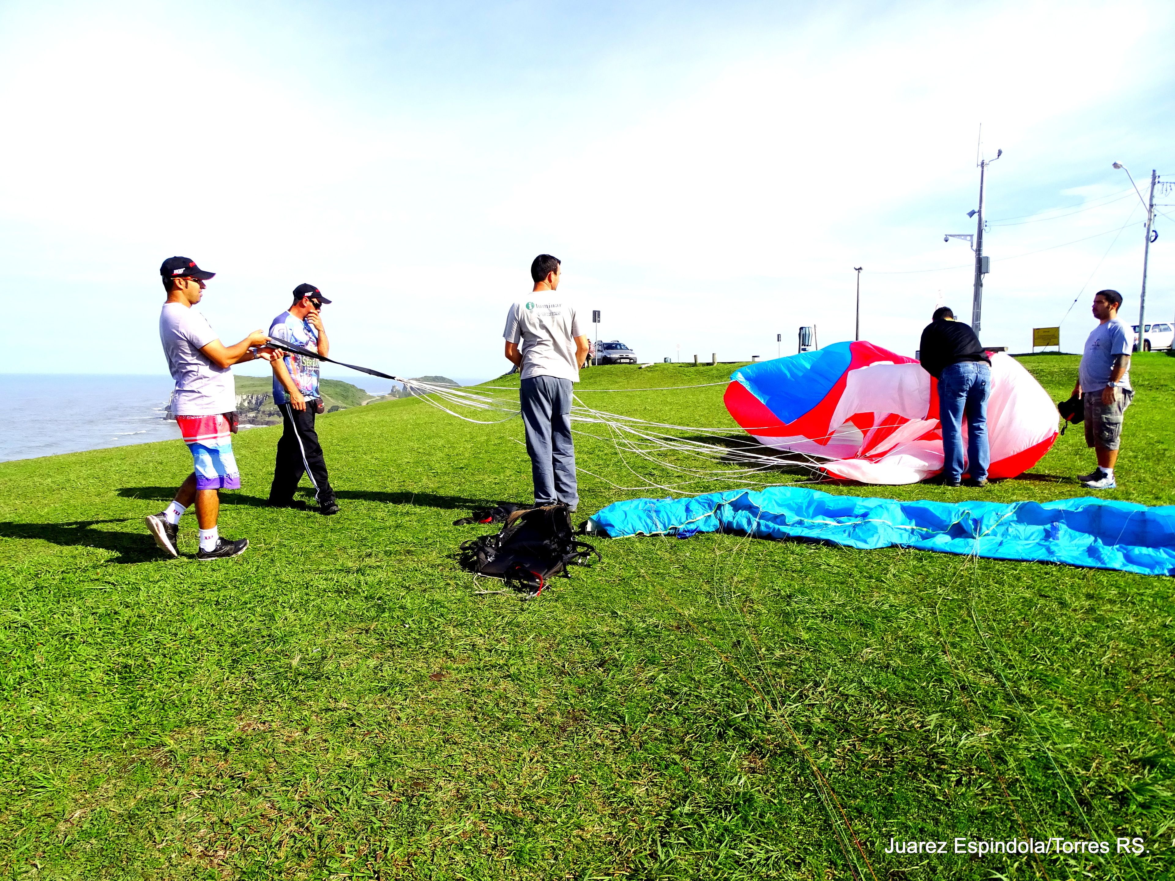 Un campo cubierto de hierba con gente preparando una cometa grande.