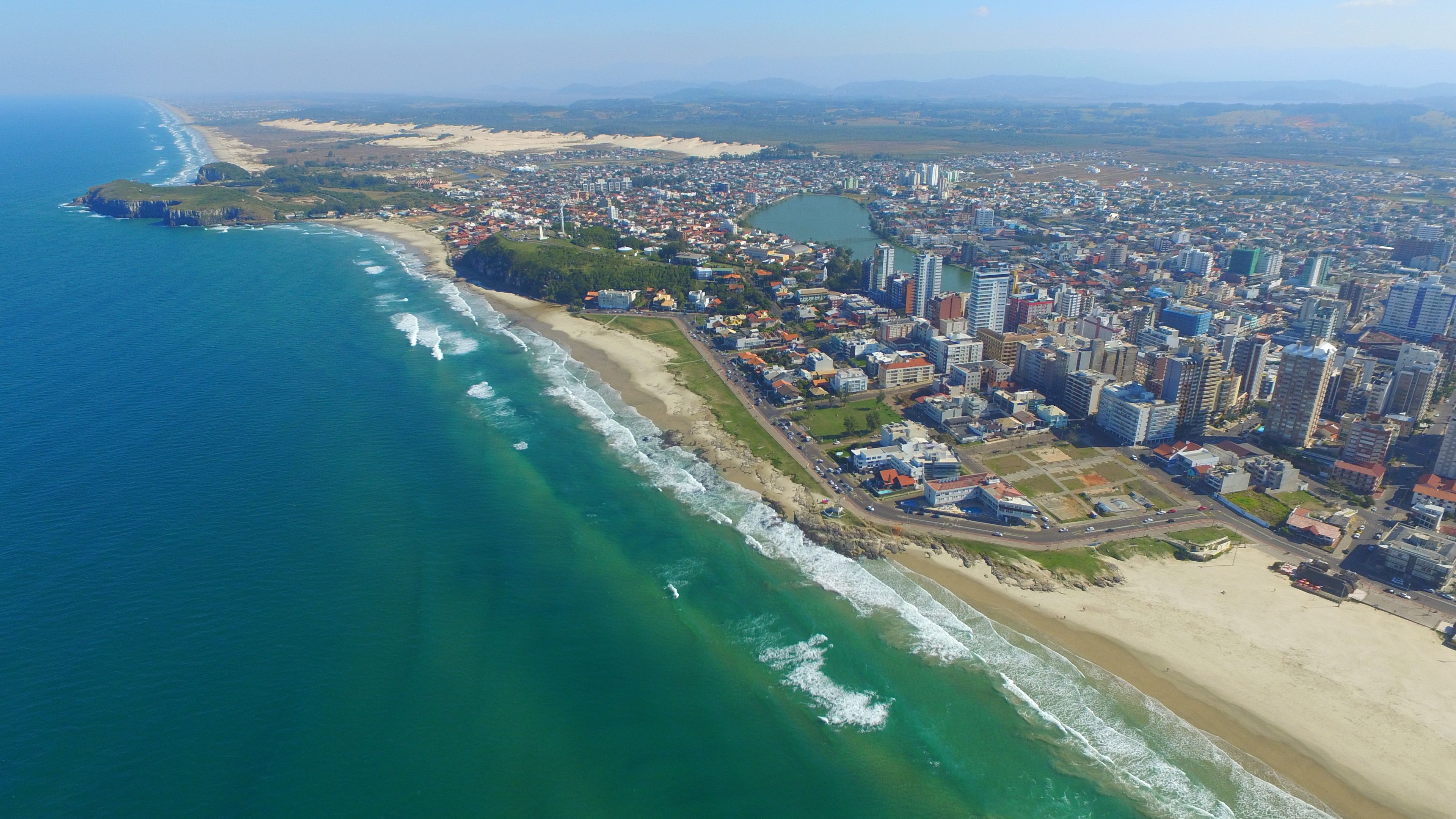 An aerial view of a coastal city with a beach, residential areas, and high-rise buildings.