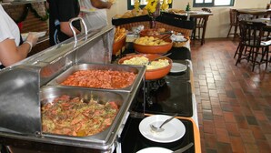 A buffet setup with various food items and a brick floor. - Recanto da Prainha (Torres)