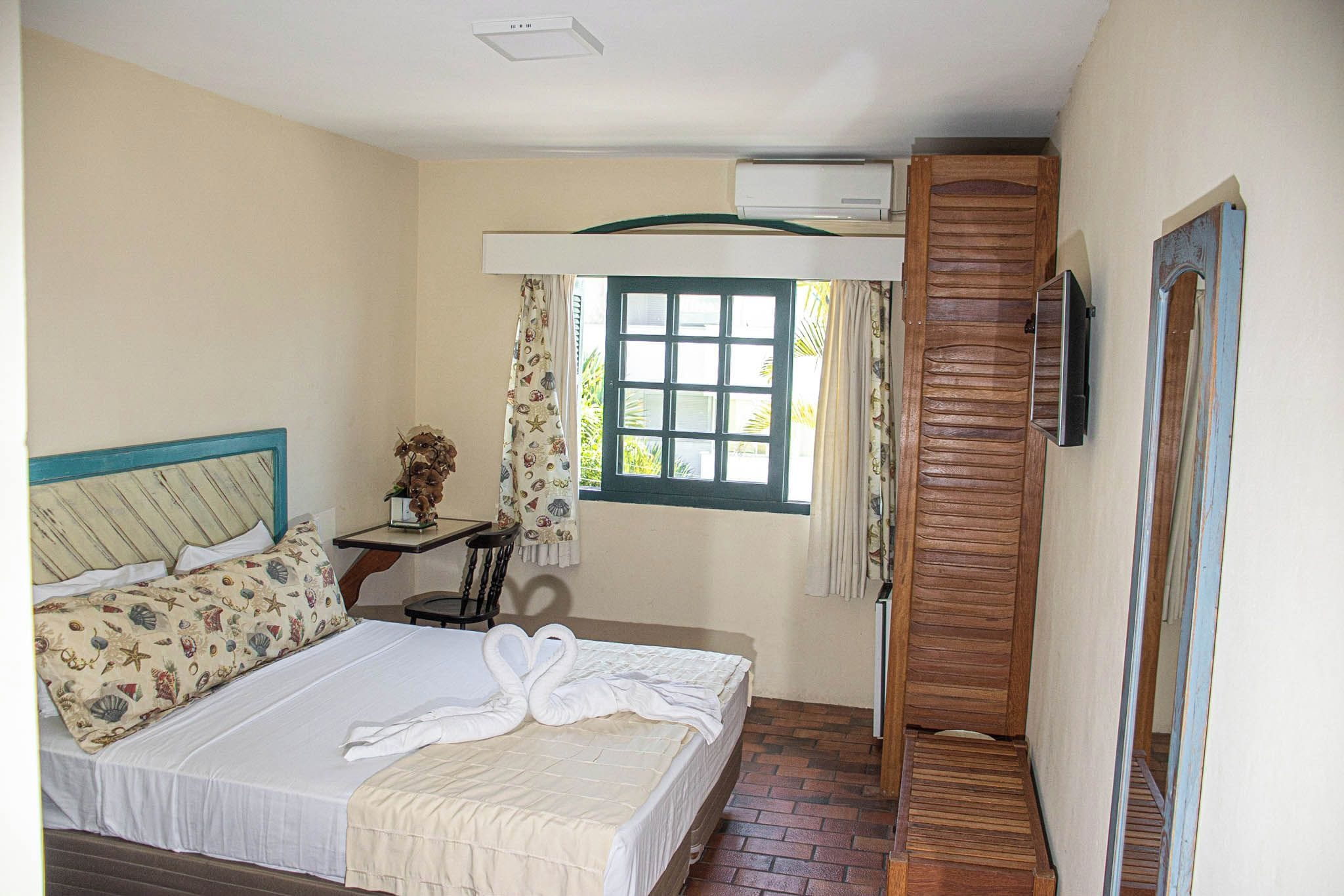 A bedroom with a bed, a nightstand, a window, and a wooden door.
