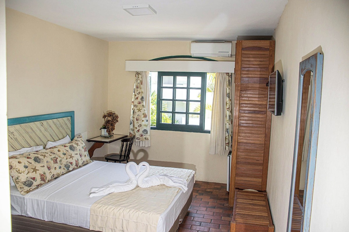 A bedroom with a bed, a nightstand, a window, and a wooden door.