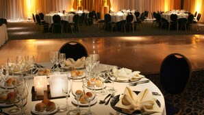 A banquet hall with round tables set for a formal event, featuring white tablecloths, glassware, and floral centerpieces. - Ariston Hotel (Rosario)