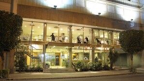 A modern hotel with a glass facade, multiple floors, and a well-lit entrance. - Ariston Hotel (Rosario)
