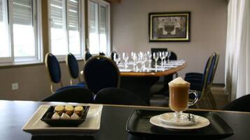 A dining area with a table set for two, a tray with a dessert and a beverage, and a window with blinds.