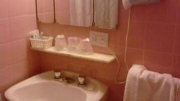 Casa de banho com lavatório, secador de cabelo, toalha e espelho.