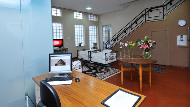 Ein geräumiger Wohnbereich mit einem Holztisch, einem Computer, einer Couch, einer Treppe und einem Esstisch mit Blumen.