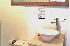 Un baño con un lavabo blanco, un espejo y un inodoro.