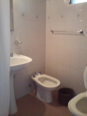 A small bathroom with a sink, a bidet, and a toilet. - Hotel Residencial Eurostop (Villa General Belgrano)