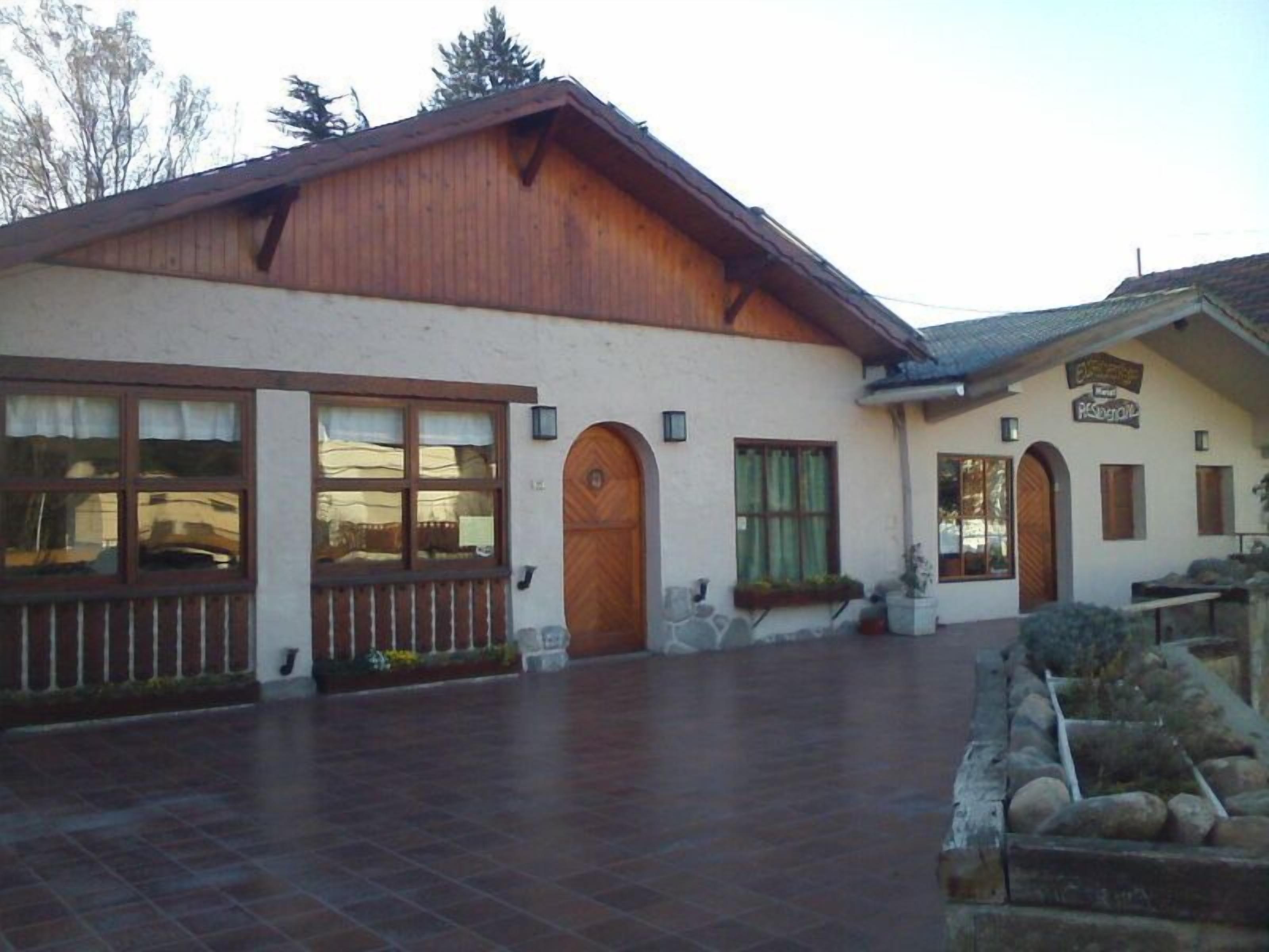 A building with a large wooden entrance, a stone pathway, and a sign indicating a restaurant.