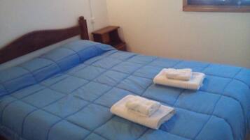 Una cama con un edredón azul y dos toallas dobladas.