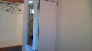 Ein schmaler Flur mit einem Holzregal links und einer Schiebetür zum Badezimmer.