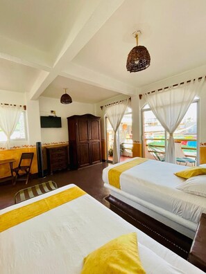 A hotel room with two beds, a desk, a TV, and a view of the outside. - Hotel Casa de la Palma Bed and Breakfast (Zihuatanejo)