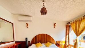 A hotel room with a wooden bed, a wooden bench, a desk, and a large mirror. - Hotel Casa de la Palma Bed and Breakfast (Zihuatanejo)