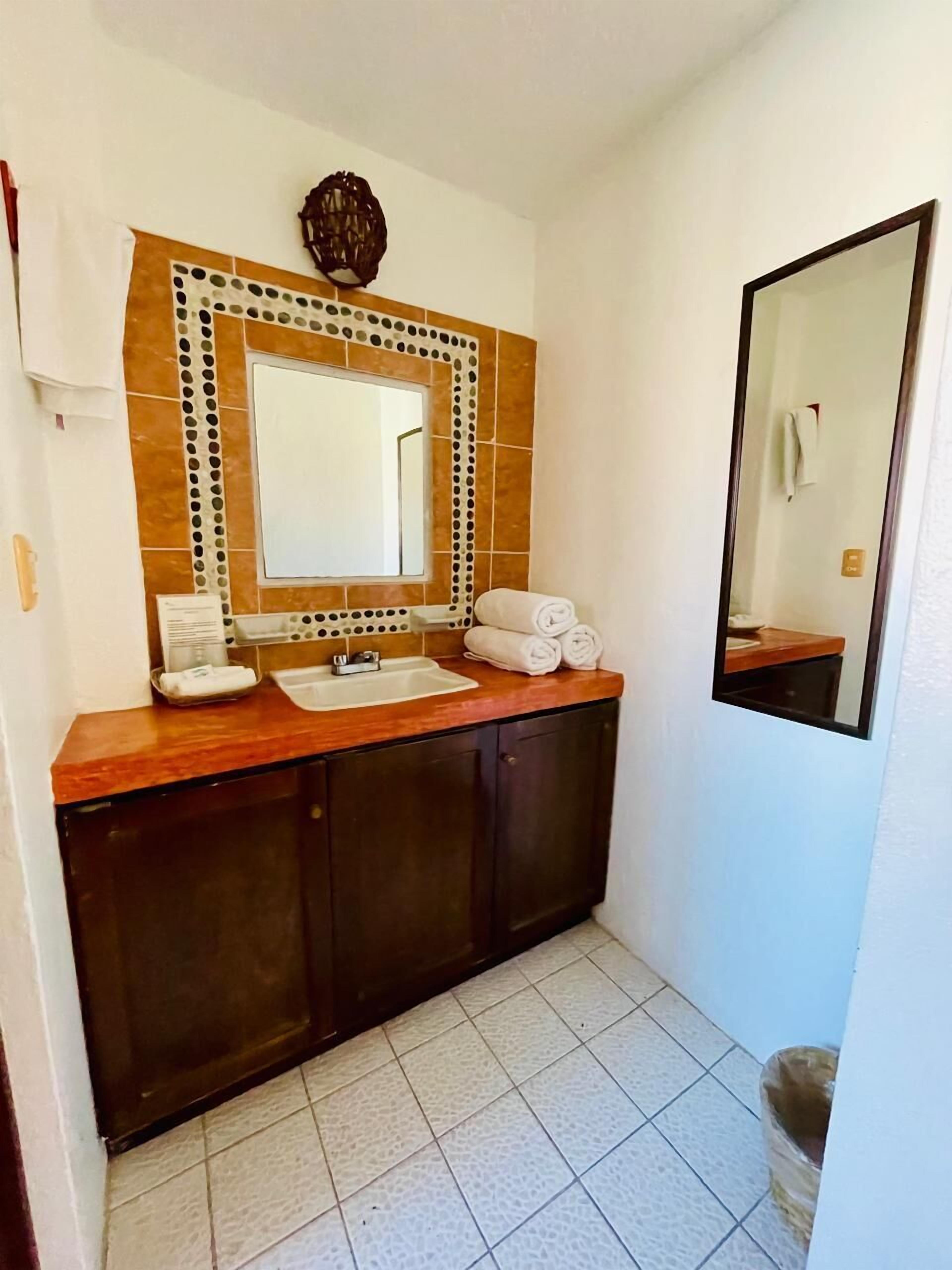 A bathroom with a wooden vanity, a large mirror, and a tiled floor.