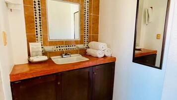 A bathroom with a wooden vanity, a large mirror, and a tiled floor.