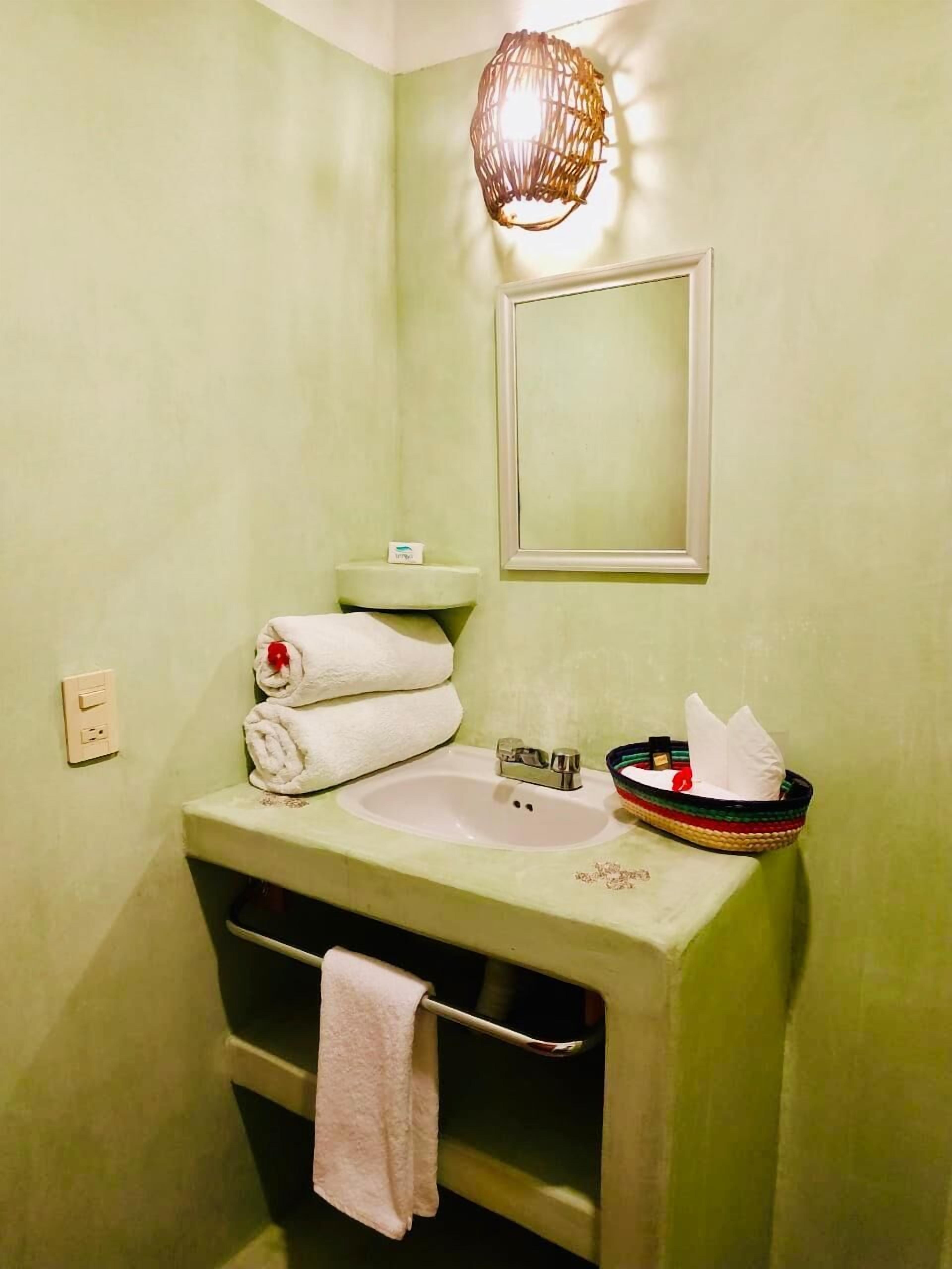 A bathroom with a green sink, a mirror, and a towel rack.