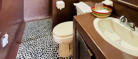 A bathroom with a brown vanity, a white toilet, and a patterned floor.