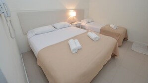 A hotel room with two beds, a bedside lamp, and a telephone. - Acqua Hotel (Mar del Plata)