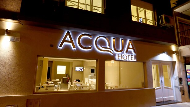 The exterior of the Acqua Hotel with a well-lit entrance and visible indoor seating area. - Acqua Hotel (Mar del Plata)