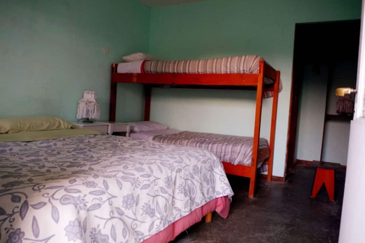 Un dormitorio con literas, una mesita de noche pequeña y una silla.