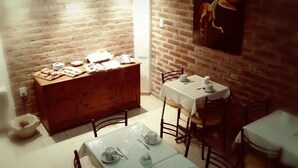 A dining area with a brick wall, a wooden cabinet with food items, and a table set for two.