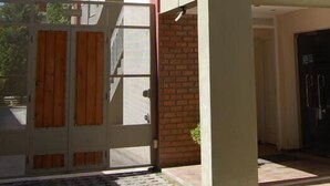 A building entrance with a glass door, a brick wall, and a black door.