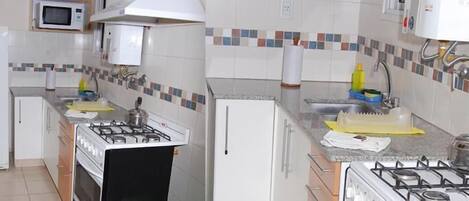 Cocina compacta con estufa a gas, microondas y refrigerador.