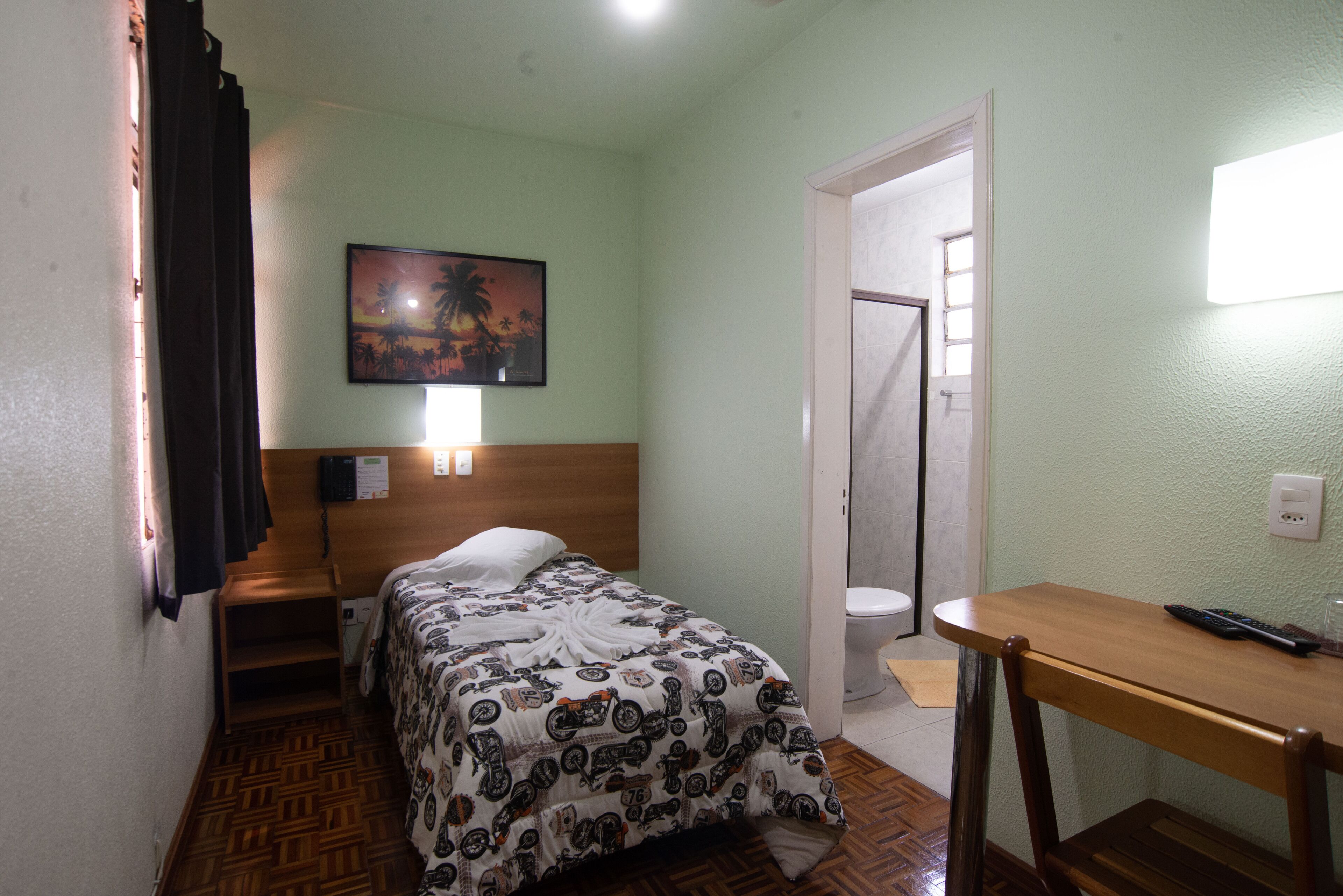 Een hotelkamer met een bed, een bureau, een douche en een schilderij aan de muur.