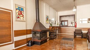 Amplia sala de estar con chimenea de leña, paneles de madera y mobiliario moderno.