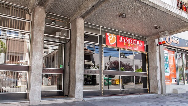 El exterior del Hotel Bandeira, con amplios ventanales y un llamativo letrero rojo.