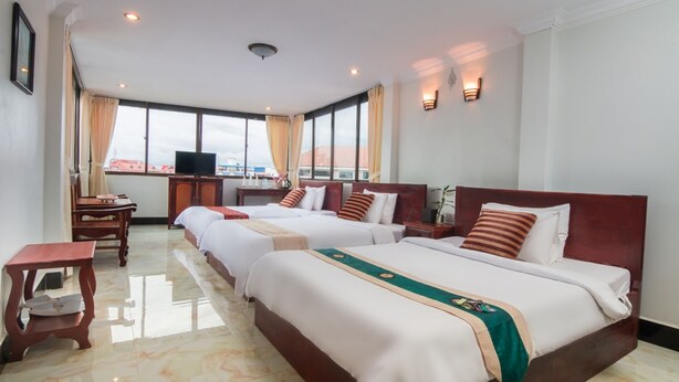 A hotel room with two beds, a TV, a desk, and a view of the city. - Angkor Udom Guesthouse (Siem Reap)