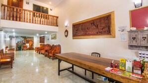 A spacious dining area with a long wooden table, several wooden chairs, and a high ceiling with a balcony. - Angkor Udom Guesthouse (Siem Reap)