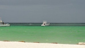 Un bateau sur une mer turquoise, avec une côte rocheuse en premier plan.
