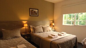 A hotel room with two beds, each with a headboard, bedside lamps, and a framed picture on the wall. - Hotel Salerno (Villa Carlos Paz)