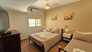 A bedroom with a bed, bedside tables, a TV, and artwork on the walls.