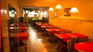 A restaurant with multiple tables and chairs, a tiled floor, and pendant lighting. - Hotel Castelmar (Mar del Plata)