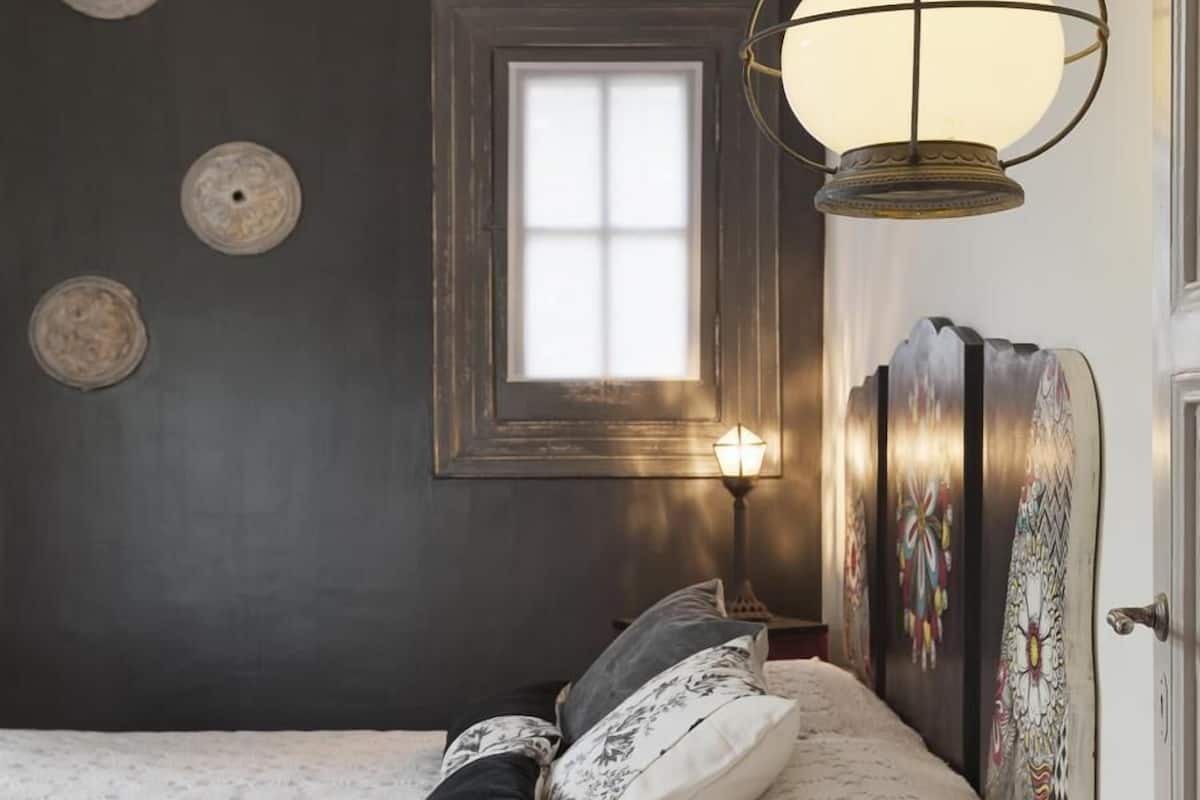 Ein Schlafzimmer mit Bett, Fenster und einer Wandlampe.