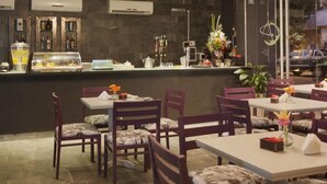 An indoor dining area with tables and chairs, a counter with a display case, and a decorative hanging light fixture. - Ambit Boulevard Hotel Boutique (Santa Fe)