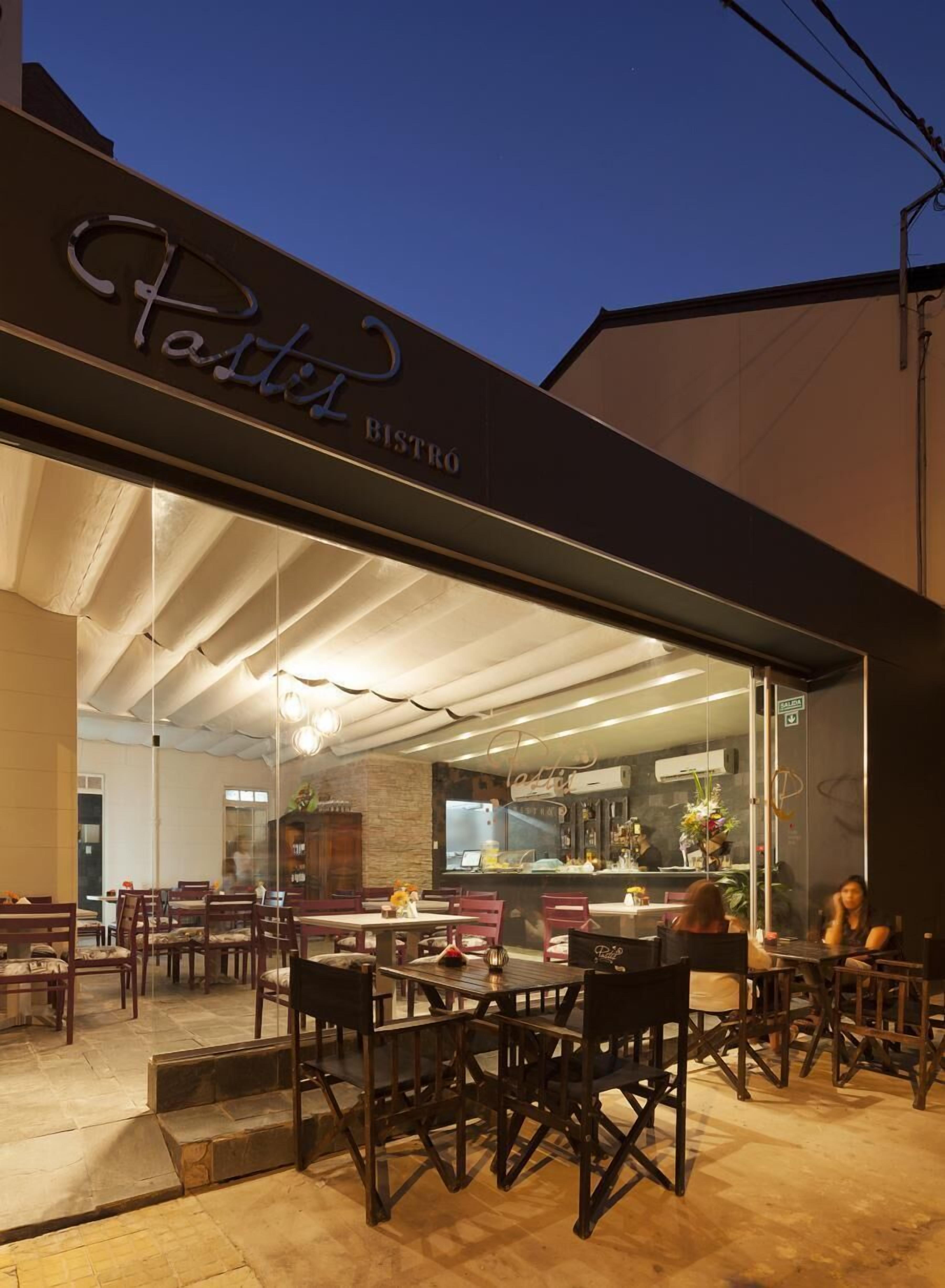 An exterior of a bistro with a modern design, featuring a prominent sign and outdoor seating area.