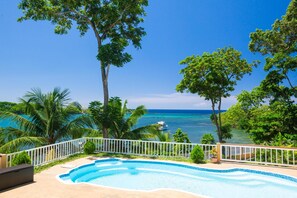 A swimming pool with a view of the ocean and palm trees. - Casa de Admirada (Roatan)