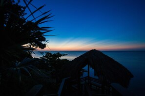 A beach view with a thatched hut and wooden deck.