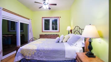 A bedroom with a bed, a nightstand, a lamp, a window, and a ceiling fan.