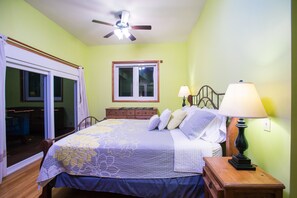 A bedroom with a bed, a nightstand, a lamp, a window, and a ceiling fan.